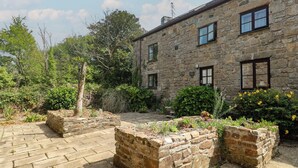 A stone building with multiple windows and a paved courtyard. - Mill House Barn (Penzance)