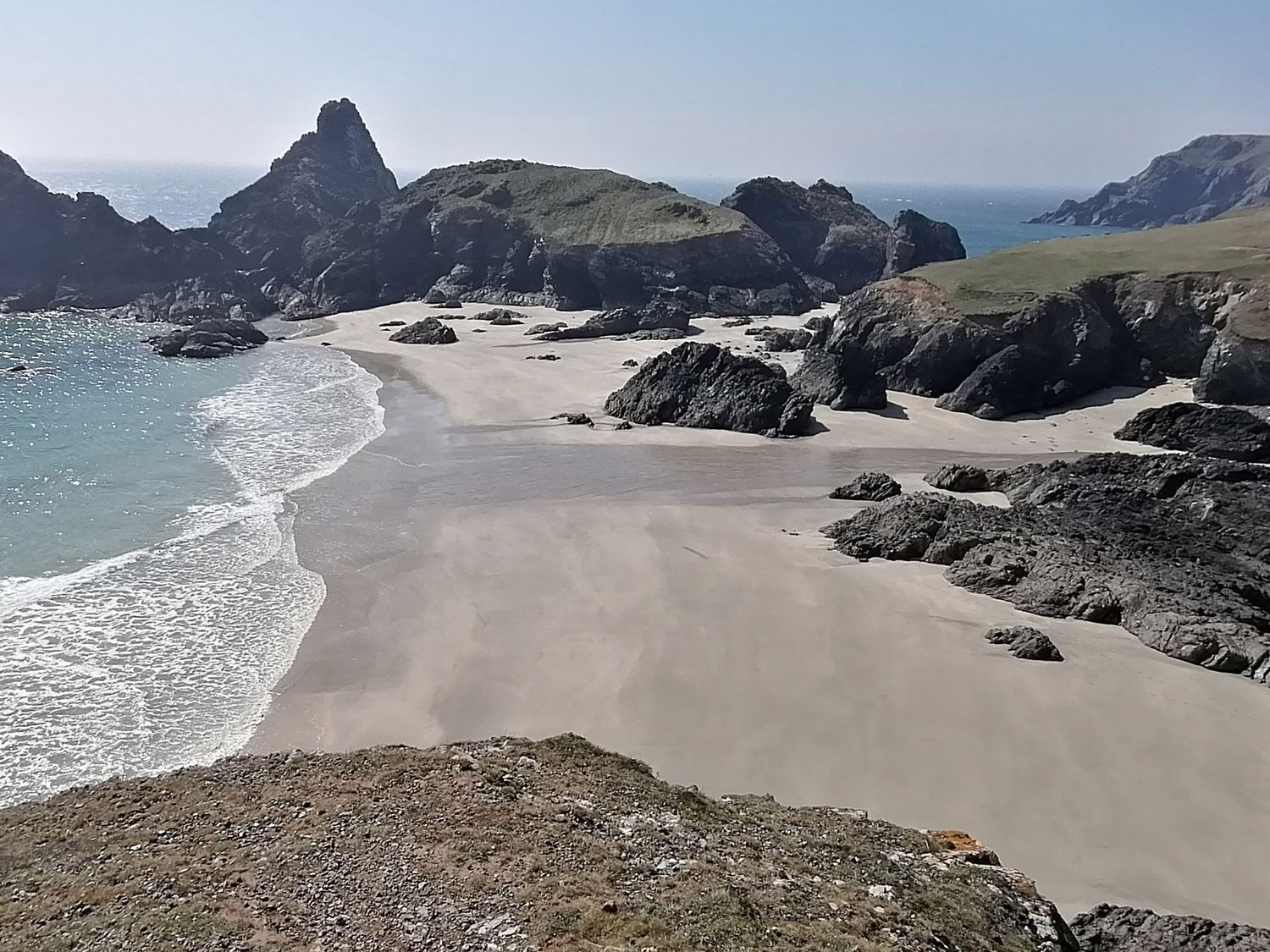 Un paisaje costero con una playa arenosa, afloramientos rocosos y una vista despejada del mar.