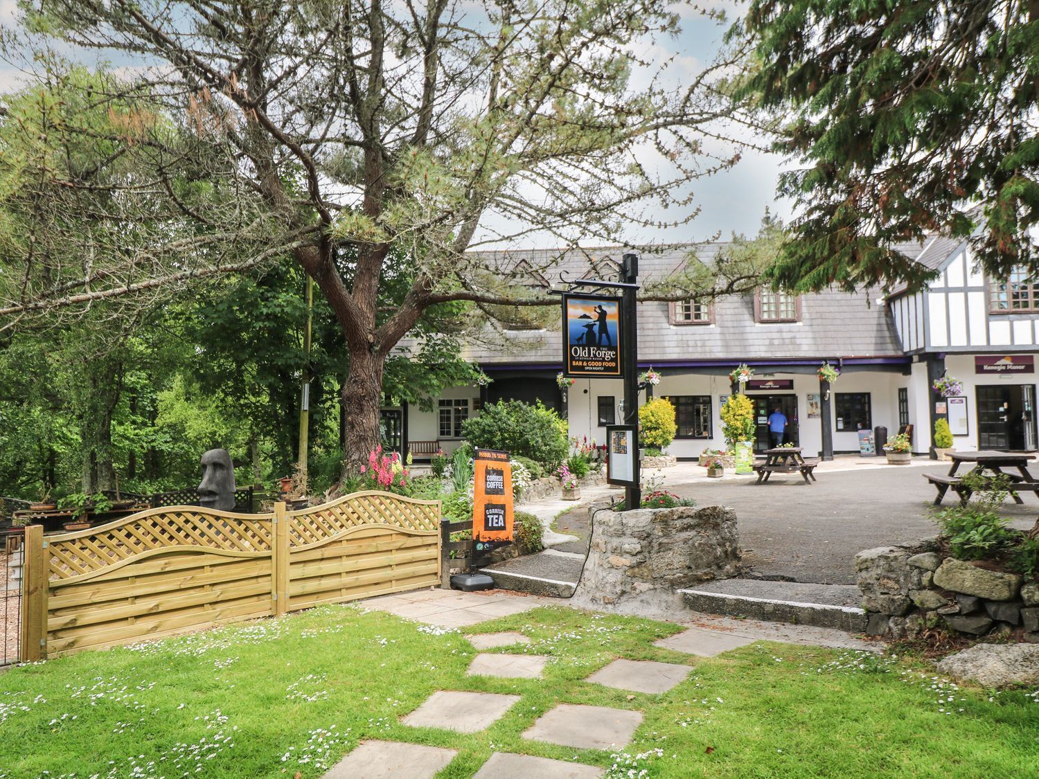 Um pub tradicional com placa, caminho de pedra e portão de madeira.