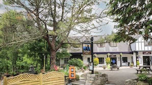 A traditional pub with a signboard, stone pathway, and a wooden gate. - Mill House Barn (Penzance)