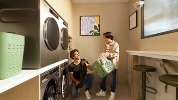A laundry room with a washing machine, a drying machine, and a green laundry basket.