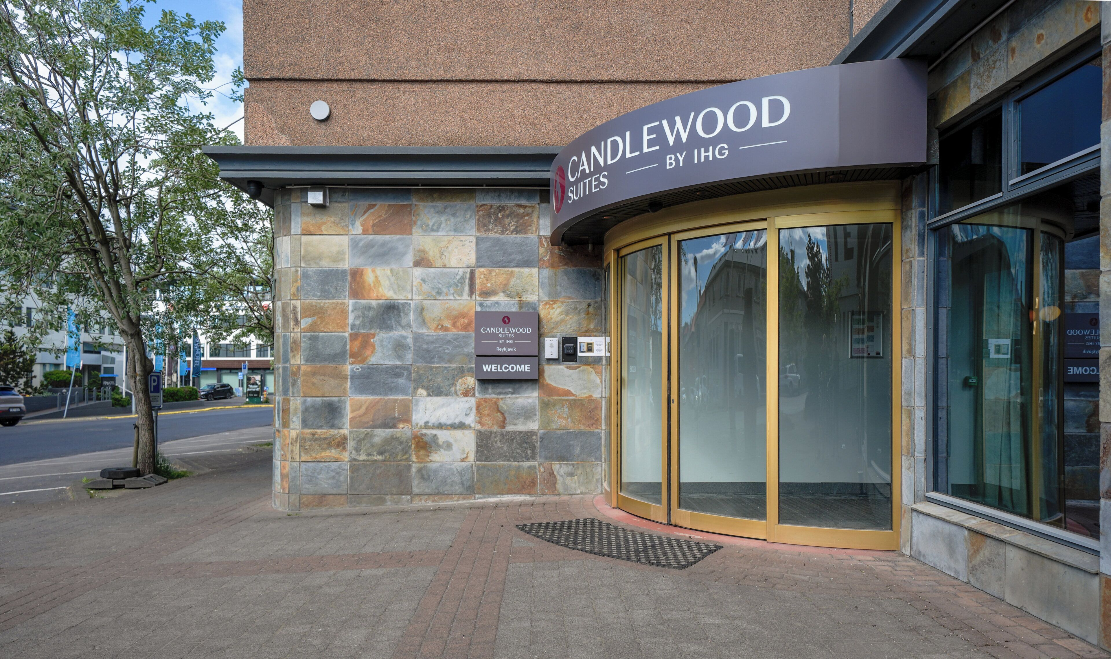 A hotel entrance with a stone facade, a sign for Candlewood Suites by IHG, and a revolving door.