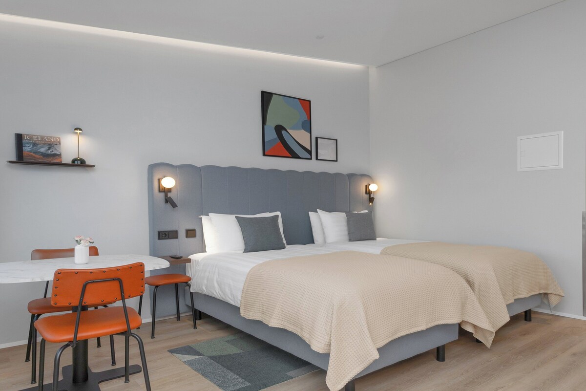 Una habitación de hotel moderna con una cama grande, un escritorio y una silla.