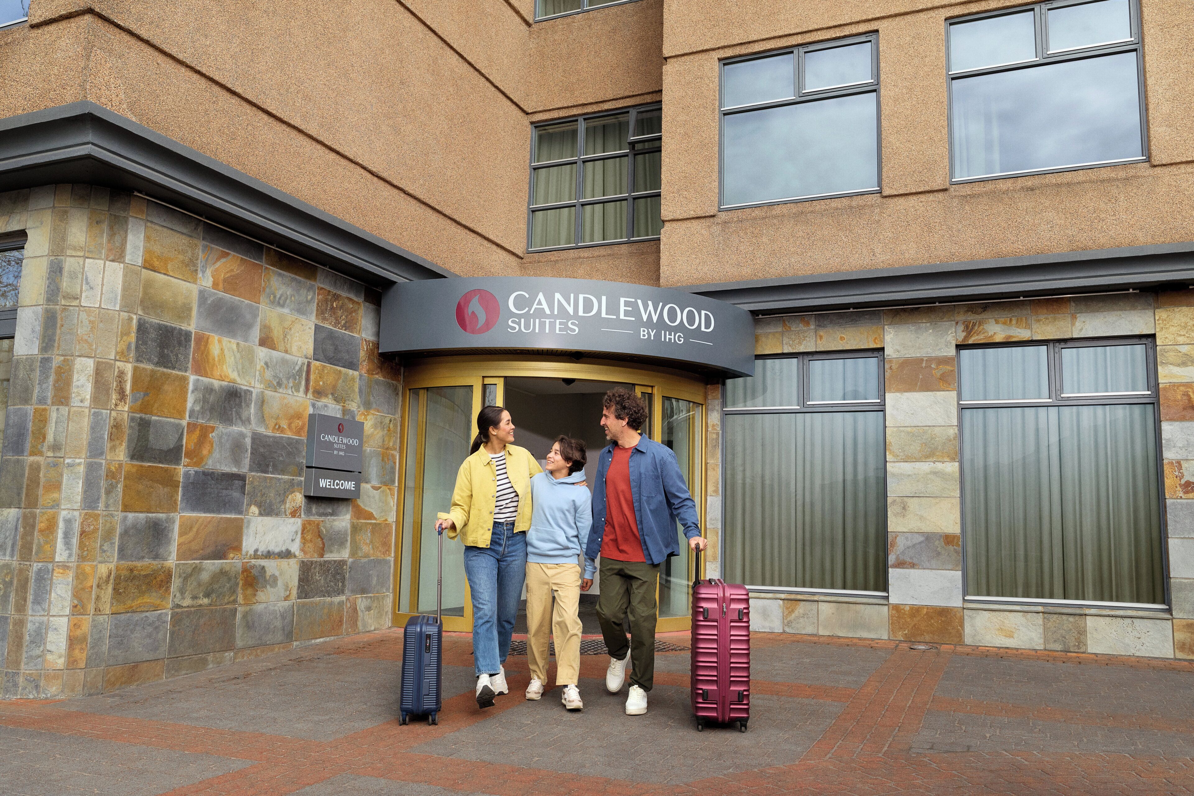 A hotel entrance with a sign reading 'CANDLEWOOD SUITES BY IHG'.