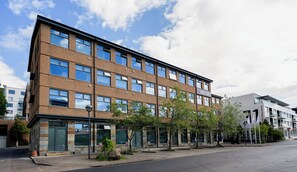 En byggnad med flera våningar, en fasad av tegel, stora fönster och ett platt tak.