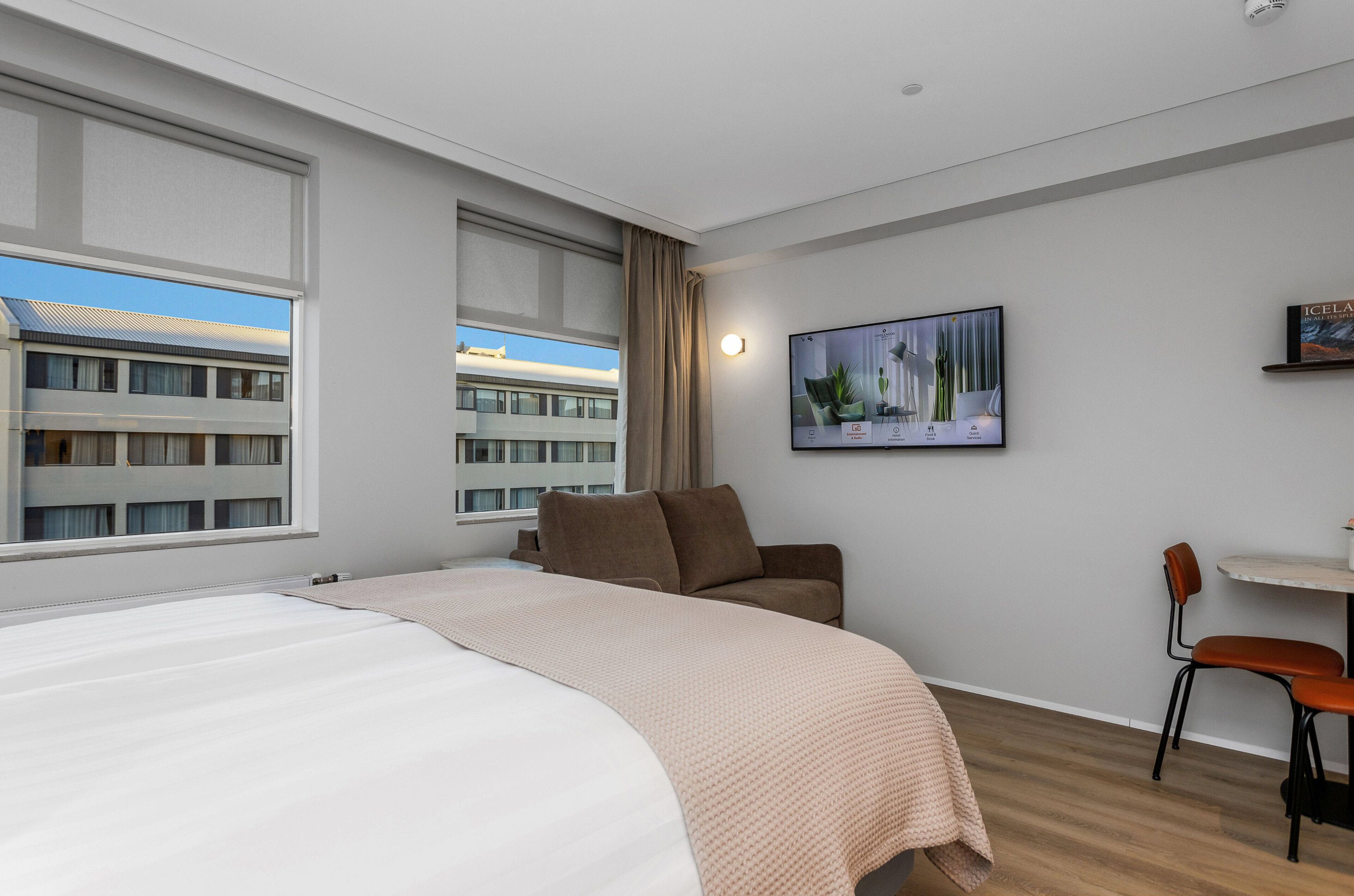 Quarto de hotel com uma cama grande, um sofá, uma escrivaninha e uma televisão.