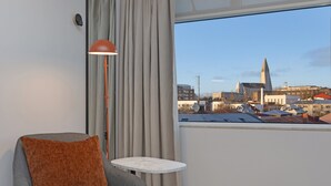 Une chambre d’hôtel moderne offrant une vue sur le paysage urbain, notamment sur le clocher imposant d’une église.