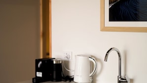 Une cuisine moderne équipée d’un lave-vaisselle encastré, d’une machine à café et d’une tasse blanche posée sur le plan de travail.