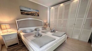 Ein ordentlich eingerichtetes Schlafzimmer mit Bett, Nachttischen, einer Lampe, einem Gemälde und einem Kleiderschrank.