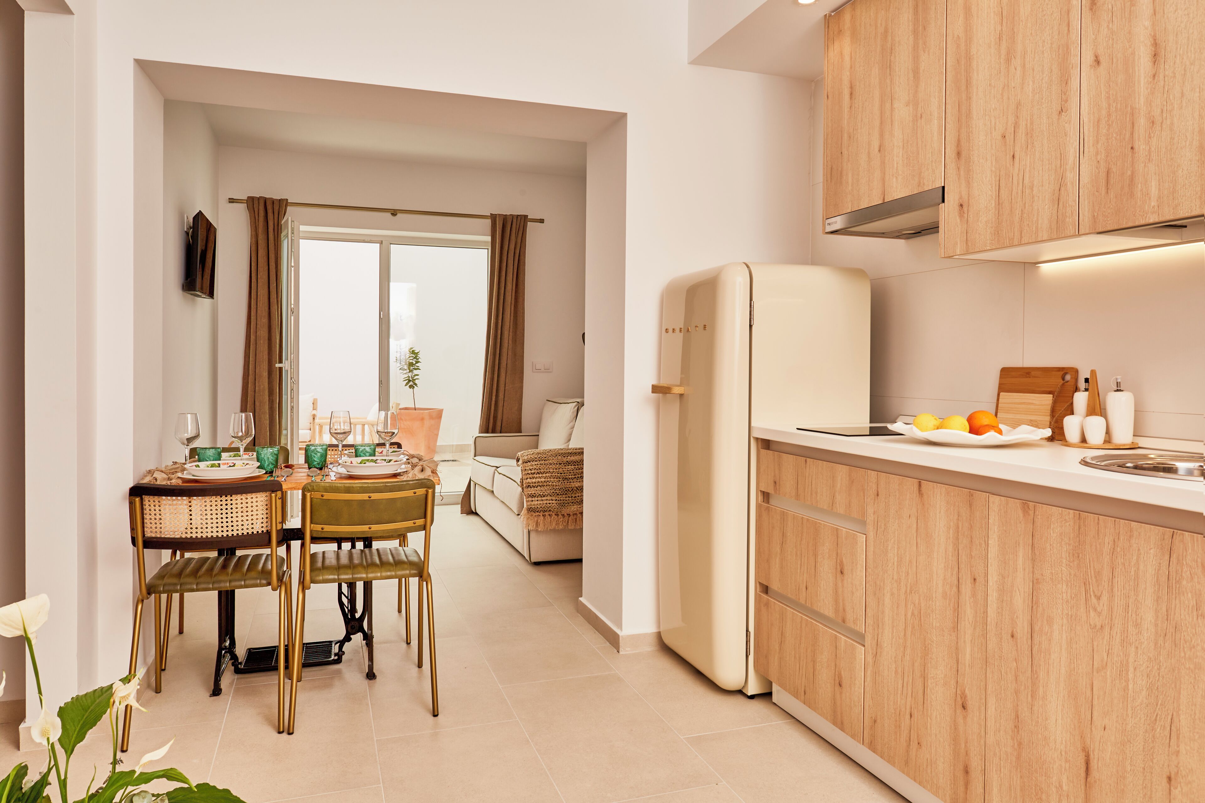 Een moderne keuken met houten kastjes, een witte koelkast, en een eethoek met een tafel en stoelen.