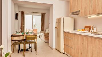 Een moderne keuken met houten kastjes, een witte koelkast, en een eethoek met een tafel en stoelen.