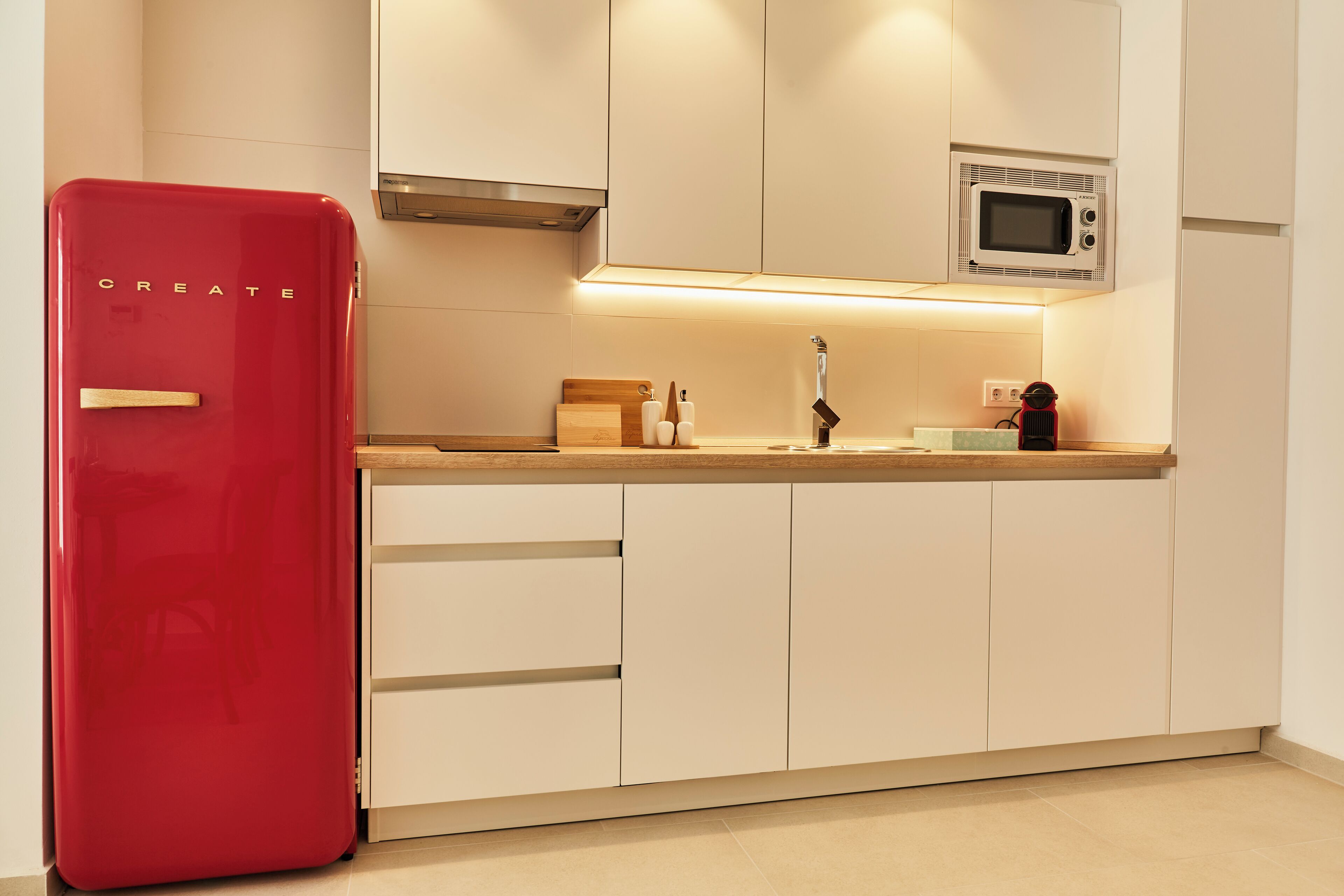 A kitchen with a red refrigerator, a microwave, and wooden cabinets.