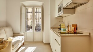 Une cuisine compacte dotée d’un four encastré, d’un évier et d’une fenêtre ornée de barreaux en fer décoratifs.