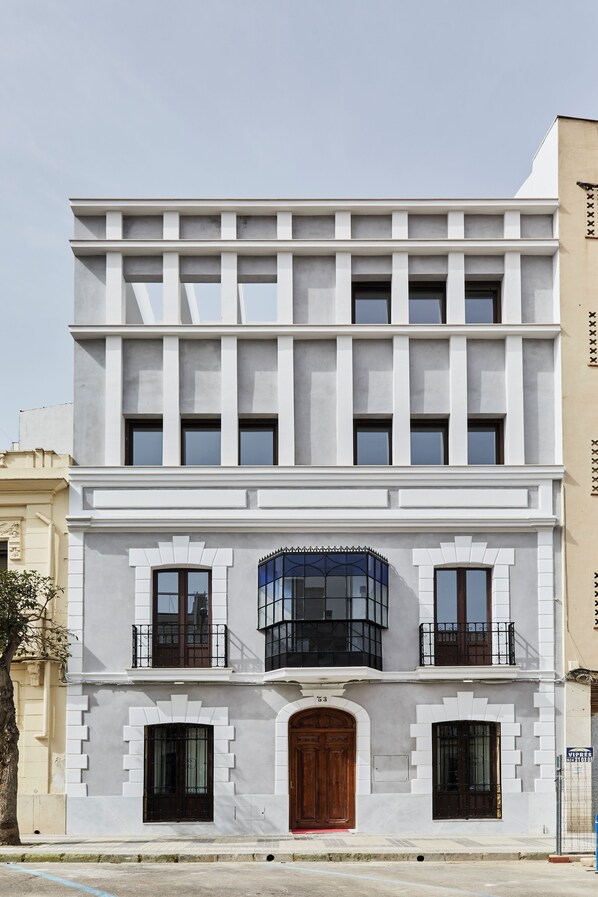 A multi-story building with a symmetrical facade, large windows, and a central entrance with a wooden door. - Lupercas Apartamentos Turísticos (Mérida)
