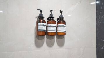 Drie flessen douchegel, shampoo en conditioner op een muur.