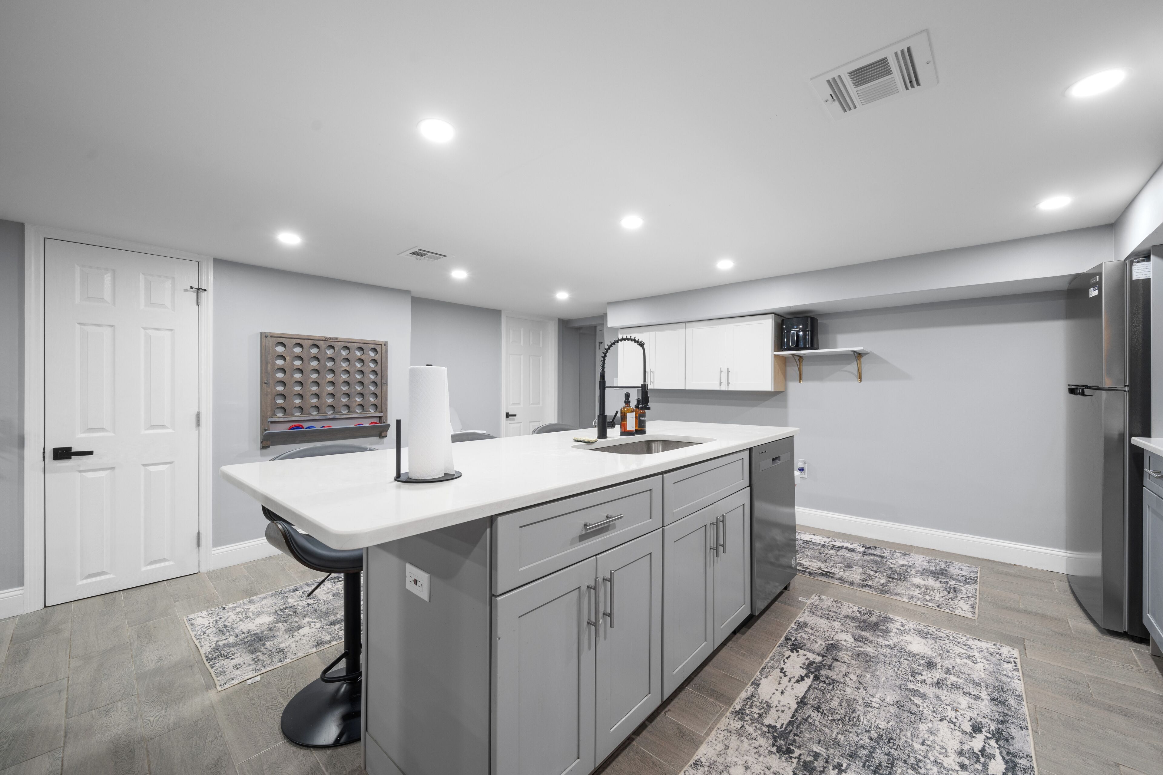 Una cocina moderna con armarios grises, encimera blanca y refrigerador de acero inoxidable.