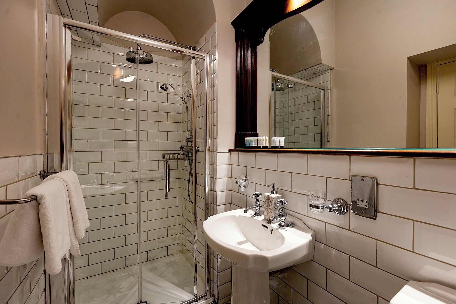 A bathroom with a glass-enclosed shower, a white sink, and a mirror above the sink.