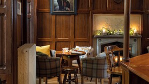 A cozy room with wooden paneling, a fireplace, and plaid furniture. - Raheen House Hotel (Clonmel)