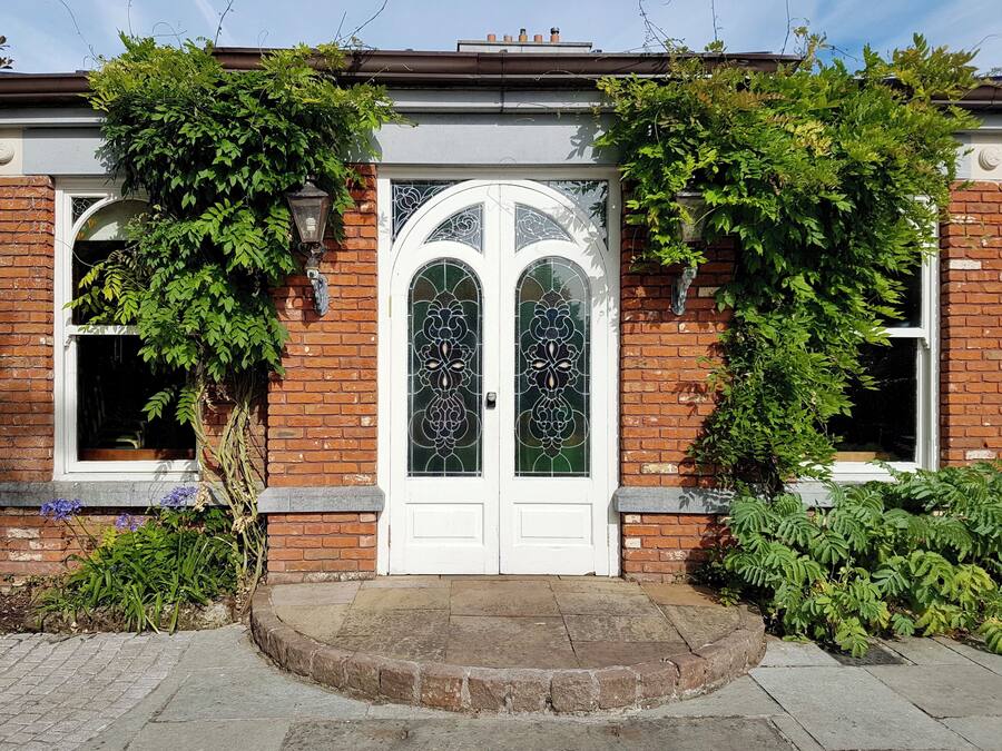 Ein Backsteinhaus mit einer weißen Tür, zwei Rundbogenfenstern und einer dekorativen Glasdoor.