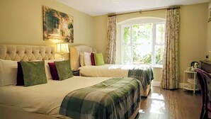 A hotel room with two beds, a large window with curtains, a painting on the wall, and a chandelier. - Raheen House Hotel (Clonmel)
