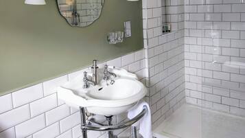Un baño con lavamanos blanco, paredes verdes y piso estampado.