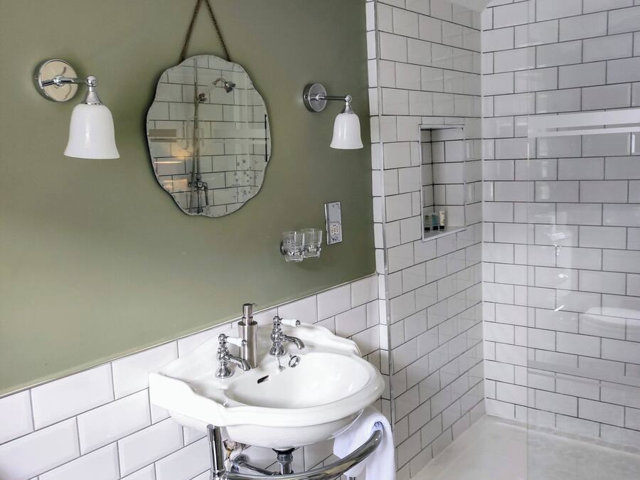 Un baño con lavamanos blanco, paredes verdes y piso estampado.