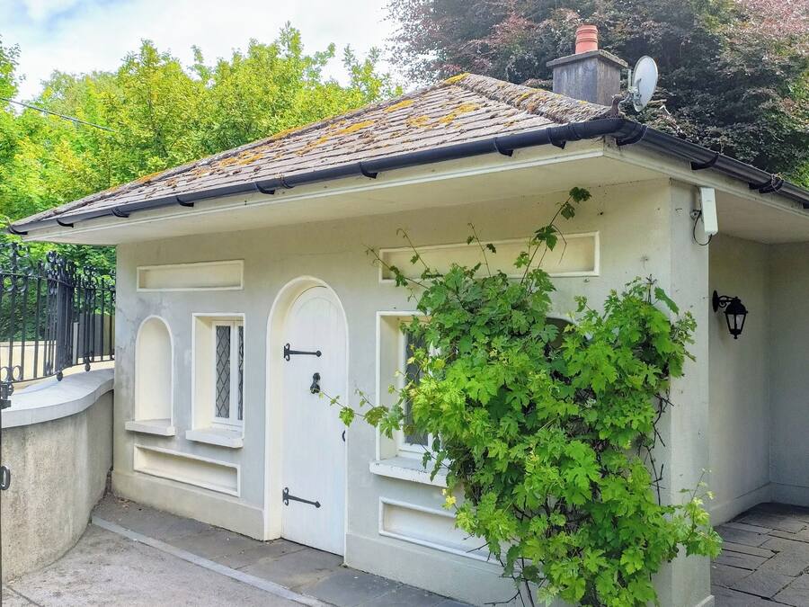 Un petit bâtiment d’un seul étage, doté d’une façade blanche, d’un toit en tuiles et d’un petit jardin agrémenté de verdure.