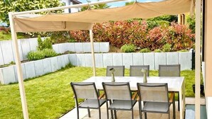 A patio with a table and chairs, a canopy, and a garden with a low wall and plants. - Family-friendly vacation apartment - four-legged friends also welcome! (Binzen)