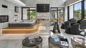 A modern living room with a large TV, a hot tub, and a bar area.