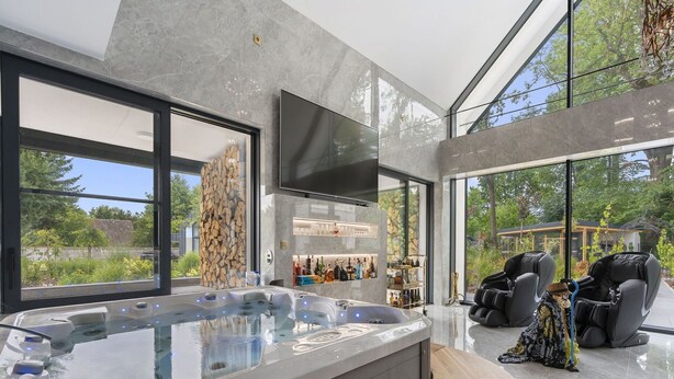A modern spa area with a hot tub, massage chairs, and a bar.