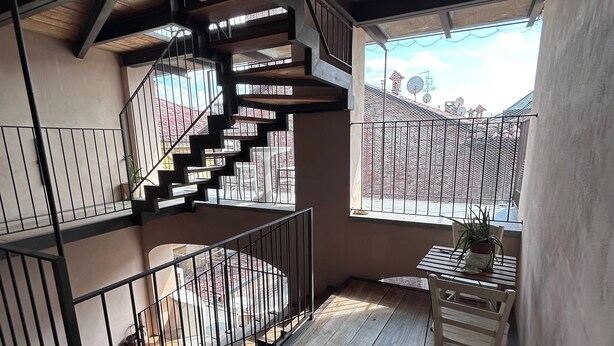 A multi-level wooden interior with a staircase, metal railings, and a view of the outside.