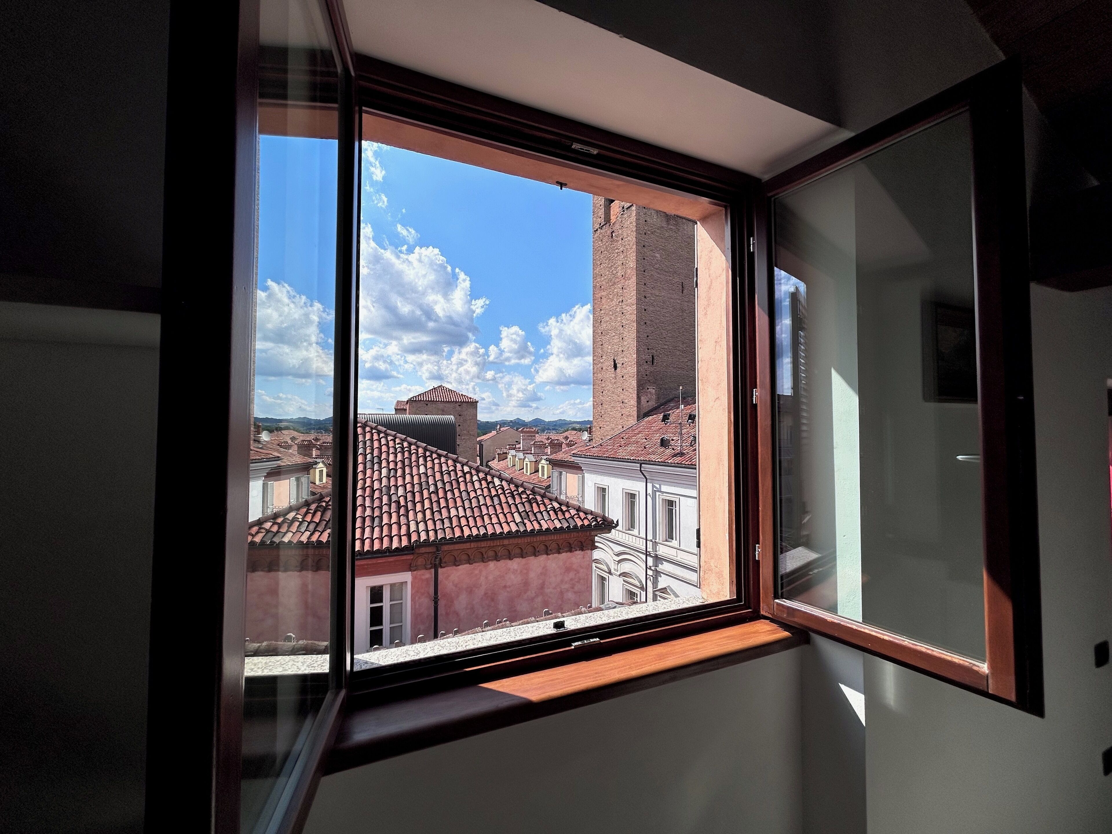 A room with a large window overlooking a cityscape, including a prominent brick tower.