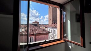A room with a large window overlooking a cityscape, including a prominent brick tower.