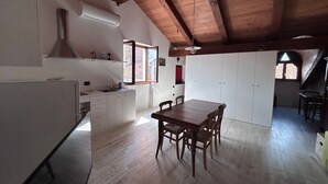 A spacious kitchen with wooden beams, a dining area with a table and chairs, and a large window providing natural light.