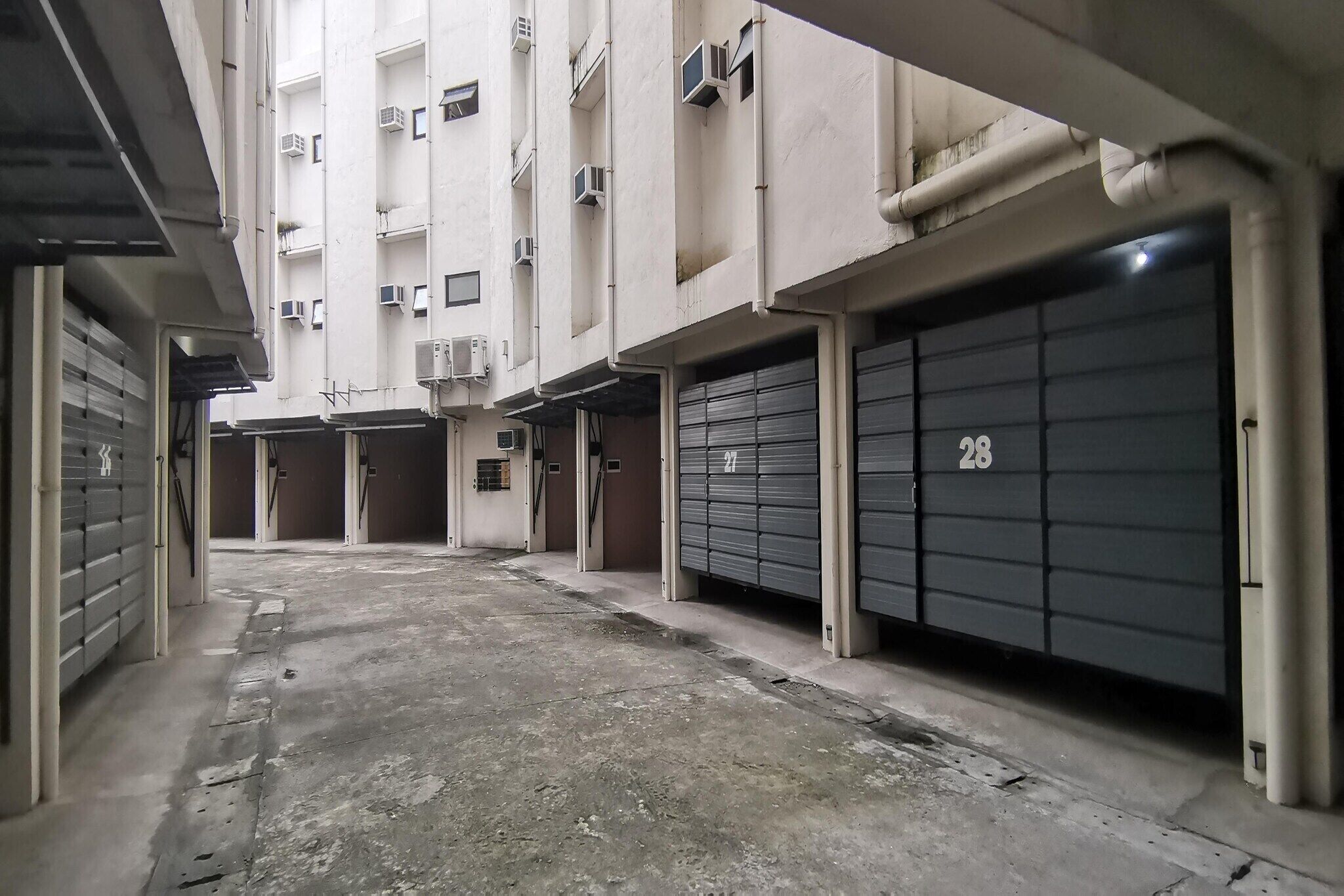 A narrow alleyway between buildings with closed garage doors numbered 27 and 28.