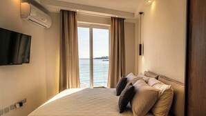 A hotel room with a bed, a TV, and a view of the sea. - Seaside Serenity at 2BR home in San Pawl il-Baħar (San Pawl il-Baħar)