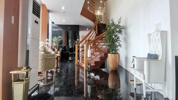 Eine moderne Hotelhalle mit Marmorboden, einer Holztreppe und einer großen Pflanze im Topf.