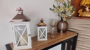 Ein Holztisch mit einer weißen Laterne, einer kleineren weißen Laterne und einer Vase mit Blumen.