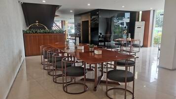 Een moderne hotel lobby met een houten receptiebalie, een grote glazen wand en een trap naar de verdiepingen erboven.