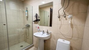 A bathroom with a glass-enclosed shower, a pedestal sink, a toilet, and a mirror. - Apartment Tbilisi (Tbilisi)