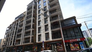 A multi-story building with balconies, a visible restaurant named 'SPAR', and parked cars on the street. - Apartment Tbilisi (Tbilisi)