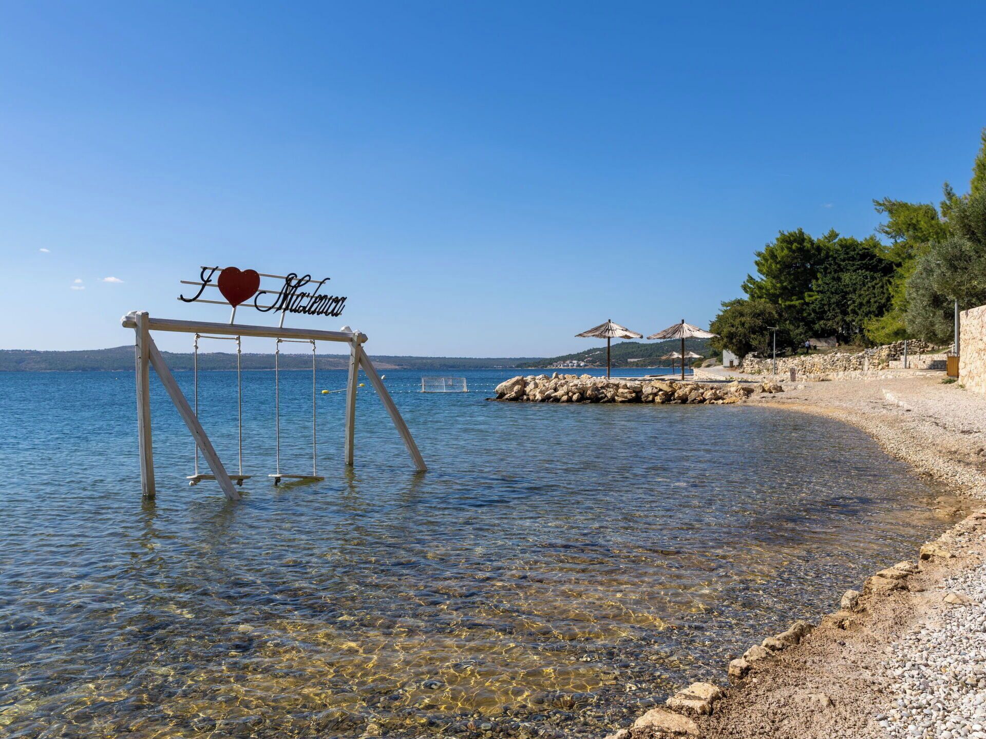A clear beach with a swing set labeled "Heart of Mallorca" and a rocky shoreline.