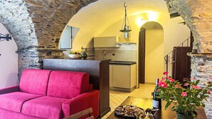 Un soggiorno accogliente con un divano rosso, un tavolo da pranzo con degli snack e una cucina sullo sfondo.