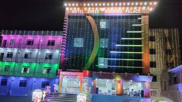 Un hôtel appelé « Hotel Shree Krishna Palace », doté d’une façade moderne et d’une enseigne lumineuse.