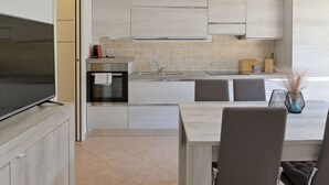 Eine moderne Küche mit Flachbildfernseher, Einbauofen und Essbereich mit Tisch und Stühlen.