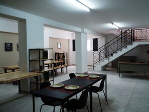 Un comedor amplio con una mesa larga dispuesta para cuatro personas, una escalera y vistas del piso superior.