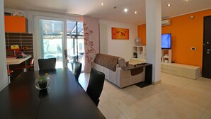A modern living room with a sofa, TV, and a dining area with a table and chairs. - Beautiful private villa with private pool, A/C, WIFI, TV, veranda, pets allowed, close to La Spezia (Ameglia)