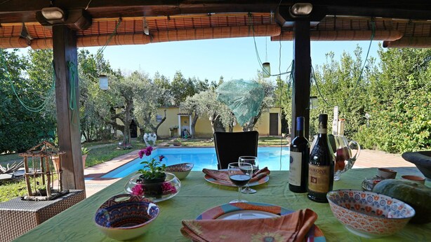 An outdoor dining area with a pool, dining table set with plates, glasses, and a bottle of wine. - Beautiful private villa with private pool, A/C, WIFI, TV, veranda, pets allowed, close to La Spezia (Ameglia)