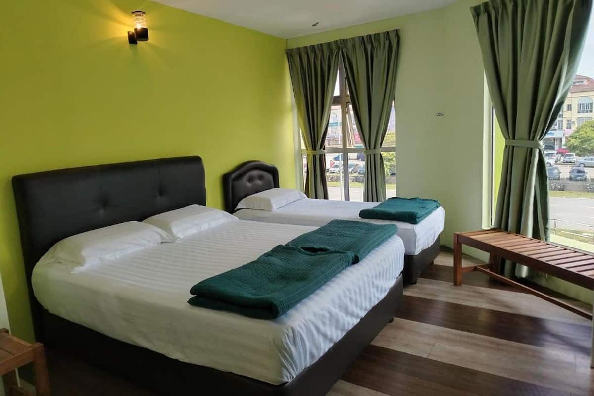 Une chambre d’hôtel avec deux lits, un banc et une fenêtre avec des rideaux.