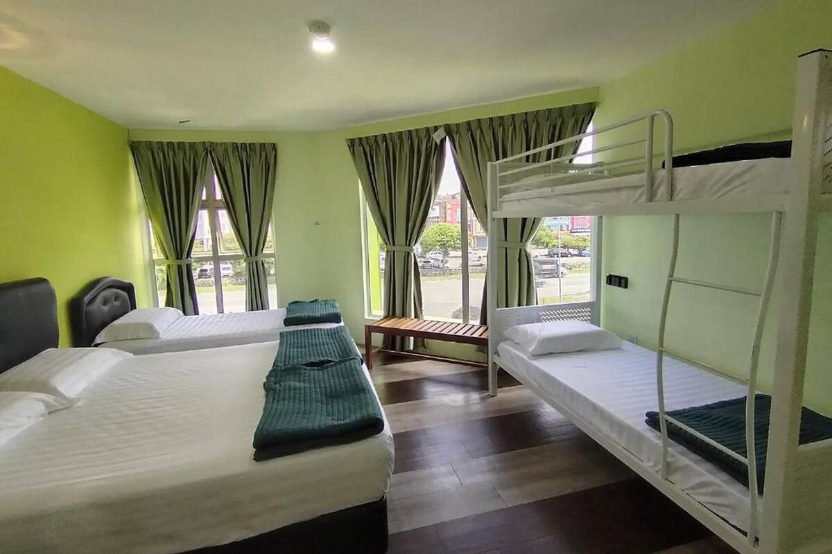 Une chambre d’hôtel avec deux lits, un banc et une fenêtre avec des rideaux.
